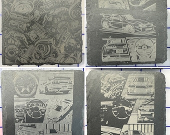 May include: Four black slate coasters with a white design of a car engine and a car. The car is a Nissan Skyline GT-R.