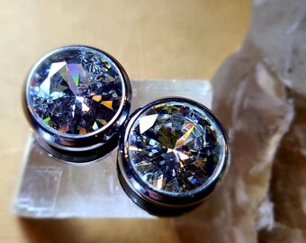May include: Two silver-toned earrings with clear, faceted, round stones. The stones have a rainbow-like sparkle.