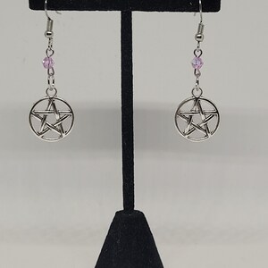 May include: A pair of silver earrings with a pentagram charm and pink crystal beads.