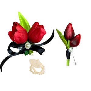 May include: A set of two red tulip boutonnieres with black ribbon and pearl accents. The larger boutonniere has three tulips and the smaller boutonniere has two tulips. A pearl necklace is also included.