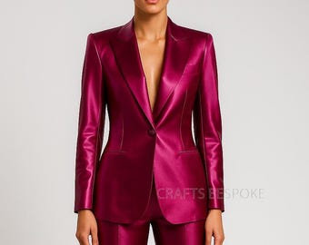 May include: A magenta-colored blazer and matching pants. The blazer has a single-button closure and a notched lapel. The text "CRAFTS BESPOKE" is visible on the lower right side of the image. The suit is made of a shiny material.