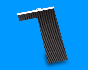 May include: A black carbon fiber panel with a white edge. The panel is shaped like a right angle and has a textured surface.