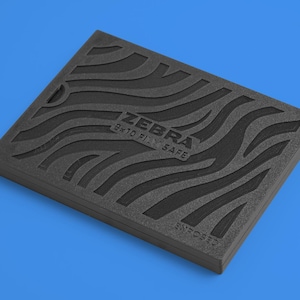 Pode incluir: Uma caixa de espuma preta com um padrão de ondas e o texto "ZEBRA 8x10 FILM SAFE" em um fundo azul. A caixa é retangular e tem uma superfície texturizada. A palavra "ENFOSED" também é visível.