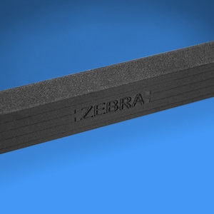 May include: Close-up of a black, textured, rectangular object with the word "ZEBRA" embossed on the surface.