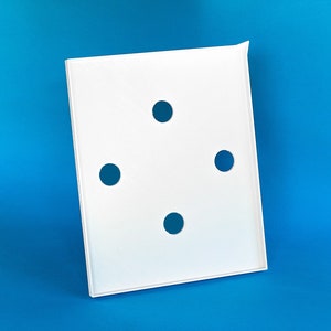 May include: White plastic square tray with four round holes cut out. The tray is on a blue background.