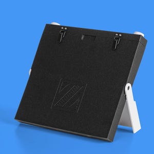 May include: Black rectangular box with a white stand. The box has a logo with a geometric design and two black latches.