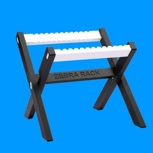 May include: A black metal stand with two white plastic shelves. The stand is labeled "ZEBRA RACK".