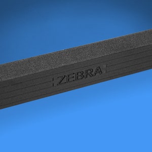 Peut inclure: Gros plan sur un objet rectangulaire noir textur&eacute; avec le mot "ZEBRA" en relief sur la surface.