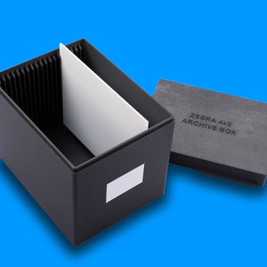 以下が含まれることがあります： 黒い収納ボックス。内側に仕切りがあり、蓋には「ZEBRA 4x5 ARCHIVE BOX」と書いてあります。