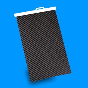 May include: A rectangular black carbon fibre sheet with a white top edge and a small handle. The carbon fibre has a woven pattern. The background is a solid blue.