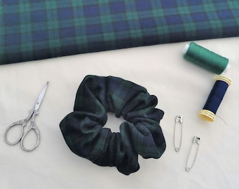 May include: A green and blue plaid scrunchie with a pair of safety pins and a spool of green thread.