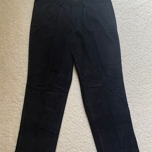 Peut inclure: Un pantalon noir à jambe droite.