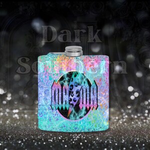 May include: A silver flask with a colorful, glittery design. The flask features a black circle with a lightning bolt and the word "MANIA" in a stylized font.