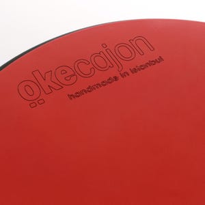 May include: A red cajon with the text "ökeçajon handmade in Istanbul" printed on the front.