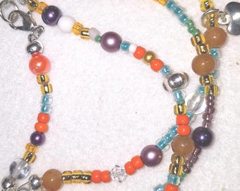 Bracelet, multi-strand. Multi colors:  orange, teal, yellow, purple. This piece features a silver heart charm. Ladies 9 inch.