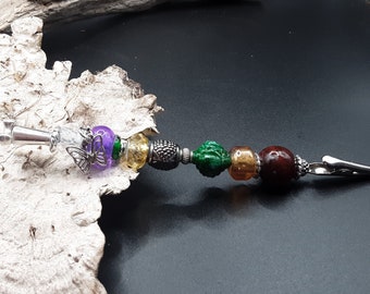 May include: A silver clip with a purple, green, gold, and brown beaded charm. The charm features a butterfly design.