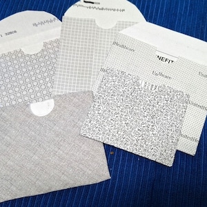 May include: Four white envelopes with different patterns. The envelopes are on a blue surface. The text on the envelopes reads "NEFIT", "UnitedHealthcare", and "Healthcare".