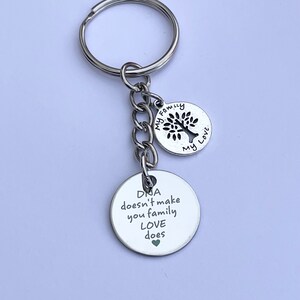 May include: Silver keychain with a tree charm and a round charm that says "DNA doesn't make you family LOVE does".