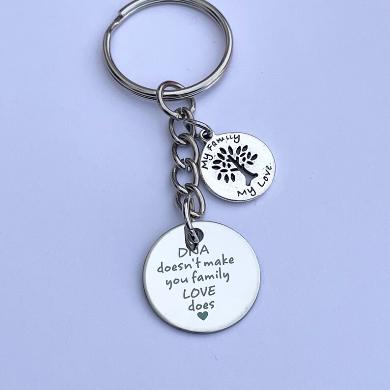 May include: Silver keychain with a tree charm and a round charm that says "DNA doesn't make you family LOVE does".