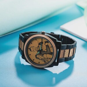 Op de afbeelding: Een gepersonaliseerd houten horloge met een zwarte en goudkleurige wijzerplaat en band. De wijzerplaat van het horloge heeft een laserge&euml;tste afbeelding van een stel. Het horloge heeft een zwarte bezel en een combinatie van zwarte en houten schakels.