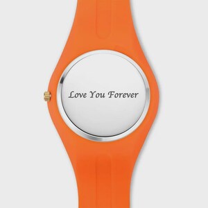 May include: Orange wristwatch with a silver face. The watch face displays the text "Love You Forever" in a simple, elegant font. The watch band is a bright orange color.