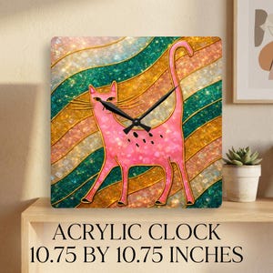 Könnte beinhalten: Quadratische Acryluhr mit einem rosa Katzendesign und goldenen Umrissen, vor einem gestreiften Hintergrund. Die Uhr ist 27,3 cm x 27,3 cm groß und hat schwarze Zeiger. Der Text "ACRYLIC CLOCK 10.75 BY 10.75 INCHES" befindet sich unten.