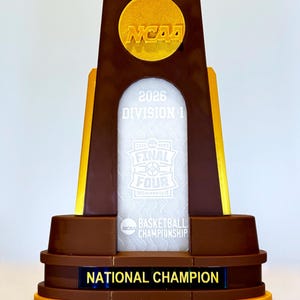 May include: A white ceramic mug with a black handle and the text "But First, Coffee" in a handwritten style. The mug is on a white surface. The mug is approximately 4 inches tall.