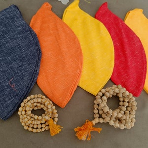 May include: Five fabric pouches in different colors: blue, orange, yellow, red, and light yellow. The pouches are arranged in a semi-circle with two strings of wooden beads in front of them.