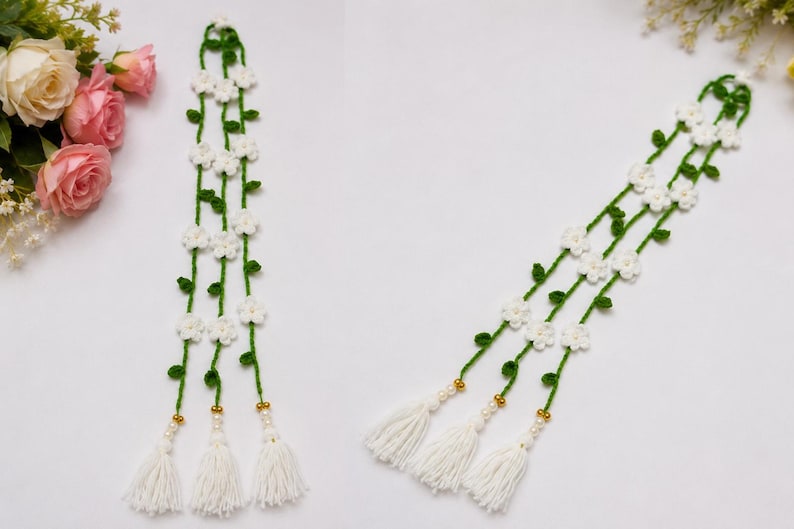 May include: A long, vertical crochet garland featuring three green yarn vines adorned with small white flowers and green leaves. Each vine terminates in a gold-toned bead, a small white pearl-like bead, and a thick white yarn tassel at the base.