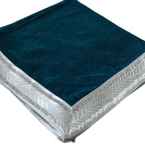 May include: Teal velvet cushion with a silver embroidered border. The border features a repeating leaf design.