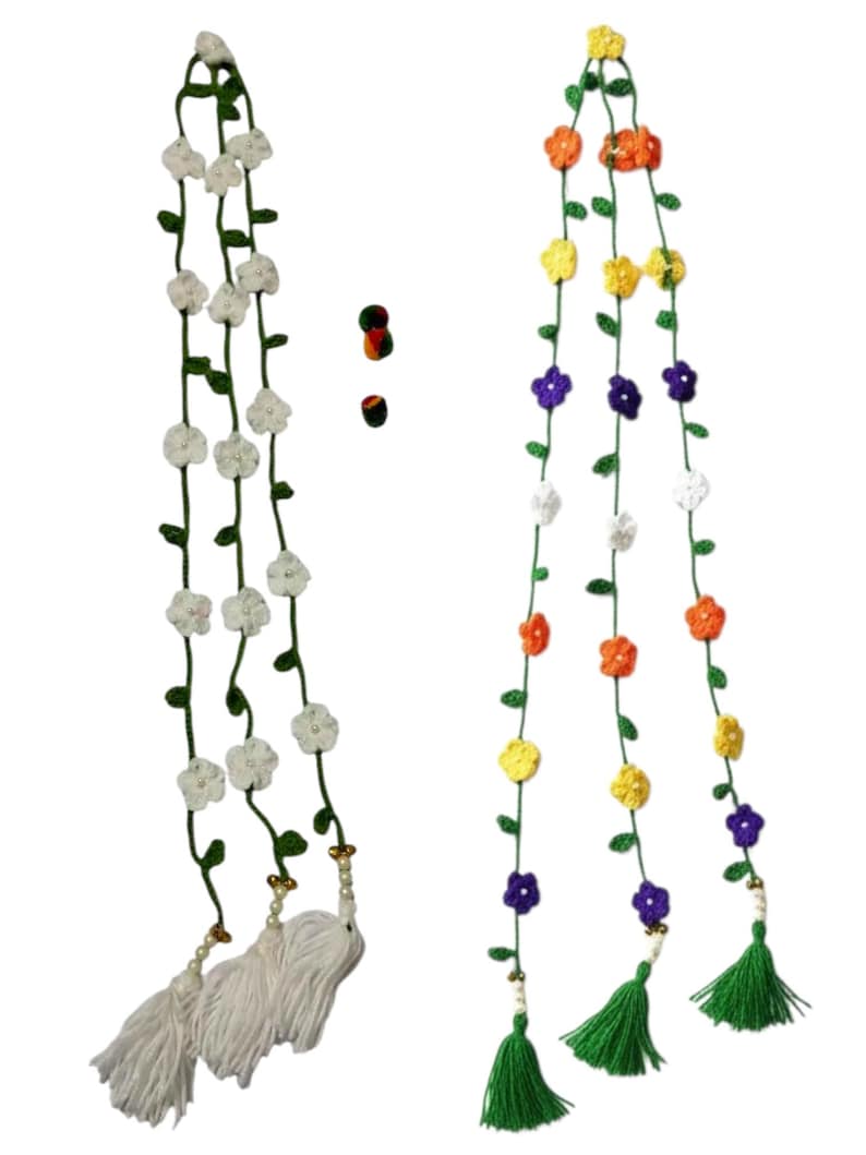 May include: Two long, vertical crochet garlands featuring green vines with small leaves. The left garland has white flowers and white tassels. The right garland has multi-colored flowers in orange, yellow, purple, and white, with green tassels.