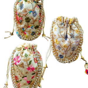 May include: Three white drawstring bags with floral embroidery and pearl trim. Each bag has a different floral pattern in shades of pink, blue, and green. The bags have gold tassels.