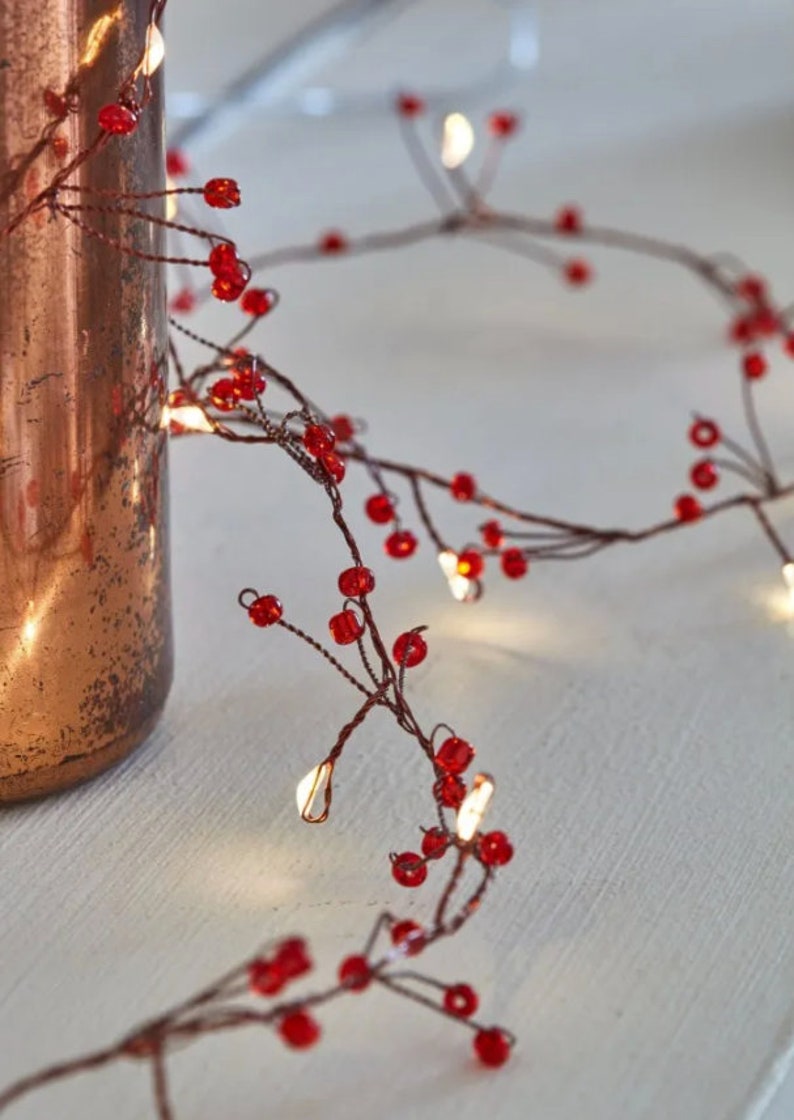 May include: A string of fairy lights with red beads, perfect for adding a festive touch to any space.