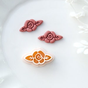May include: Three resin rose flower embellishments in pink and orange. The roses are in a simple, classic style with a single swirl in the center and two leaves on either side.