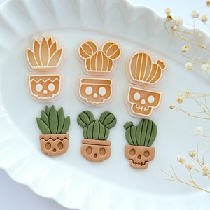 May include: Set of six silicone cookie cutters shaped like potted plants with skull details. The cutters are in shades of brown, green, and orange.