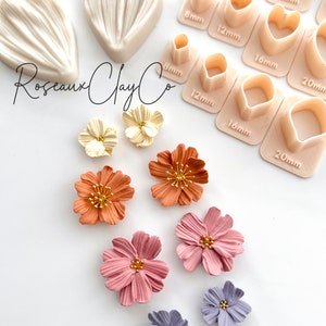 May include: A set of polymer clay flower making tools and supplies. The tools include a variety of sizes of heart and round cutters, and two silicone molds for creating flower petals. The image also shows several finished polymer clay flowers in various colors, including cream, orange, pink, and purple.