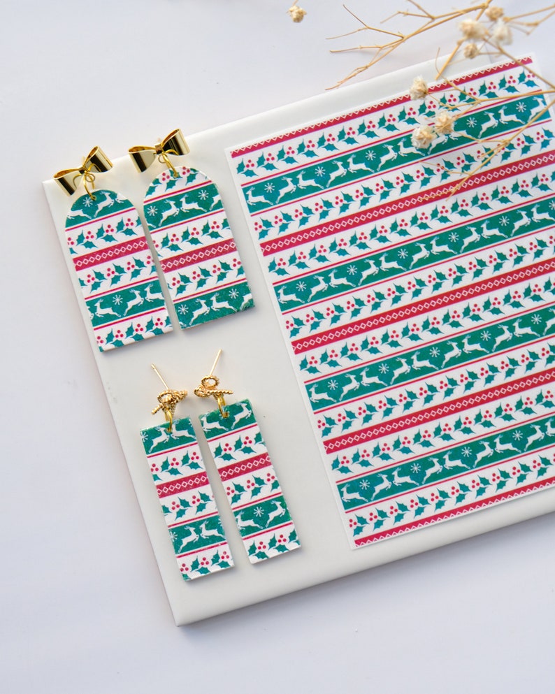 May include: A set of four Christmas-themed earrings featuring a green, red and white pattern with a reindeer design. The earrings are made of polymer clay and have gold-coloured findings.
