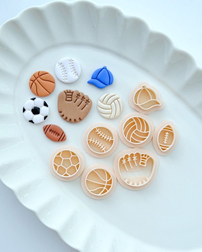 Pu&ograve; includere: Una collezione di 12 tagliabiscotti in argilla bianca e marrone a tema sportivo. I tagliabiscotti hanno la forma di una palla da baseball, una palla da basket, un pallone da football americano, un pallone da calcio, una palla da pallavolo, un guanto da baseball e un berretto da baseball.
