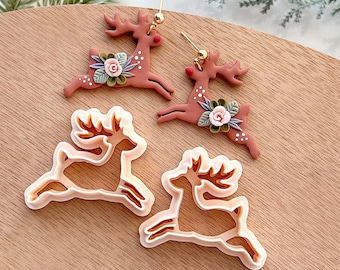May include: Two pairs of reindeer cookie cutters, one pair is brown and the other pair is white. The brown reindeer have floral accents.
