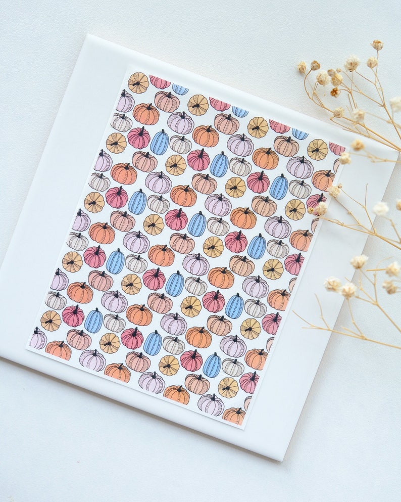 May include: A white card with a repeating pattern of colorful pumpkins. The pumpkins are drawn in a simple, cartoon style and are arranged in a diagonal pattern.