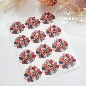 May include: A white sheet featuring eleven repeating turkey illustrations, each composed of various patterned fabric-style patches in shades of red, blue, and beige. Each turkey has a small bow at the neck. The text roseaux clay co is visible.