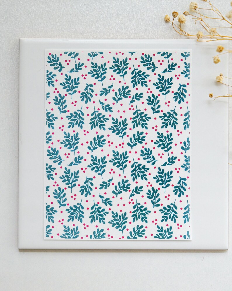 May include: A white card with a teal and pink floral pattern. The pattern features small teal leaves and pink dots.