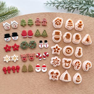 Può includere: Una collezione di formine per biscotti e pezzi di fondente decorativi a tema natalizio. Le formine hanno varie forme, tra cui omini di pan di zenzero, alberi, pupazzi di neve e fiocchi. I pezzi di fondente presentano disegni simili in rosso, bianco e verde.