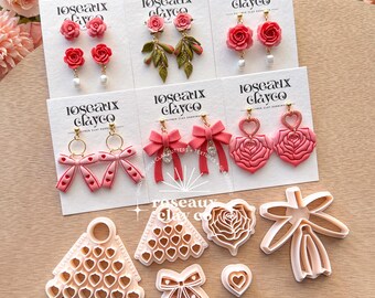 May include: A collection of handmade polymer clay earrings and cutters. The earrings feature rose, bow, and heart designs in shades of pink and red. The cutters are in the shapes of bows, hearts, and a Christmas tree.