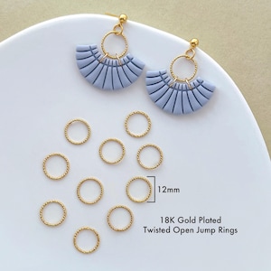 May include: Close-up of gold-plated twisted open jump rings, 12mm in diameter, and two pairs of blue fan-shaped earrings. The earrings have gold-colored posts and circular accents. The text reads "18K Gold Plated Twisted Open Jump Rings."