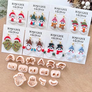 May include: Polymer clay earrings in various snowman designs, each with a festive hat and scarf, displayed on white cards. The text "loseaux clayco" is visible on the cards. Also shown are clay cutters for making the earrings.