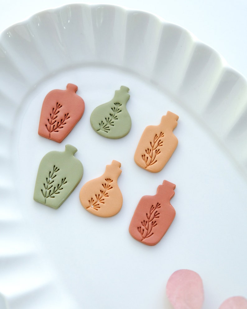 May include: Six small ceramic bottle ornaments in various shades of green, orange, and brown. Each bottle has a simple, stylized plant design.