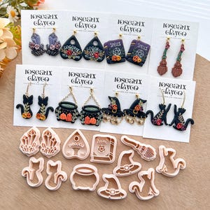May include: A collection of handmade polymer clay earrings and matching cookie cutters. The earrings feature various Halloween-themed designs, including witch hats, spell books, black cats, and cauldrons. The cookie cutters are in the same shapes.