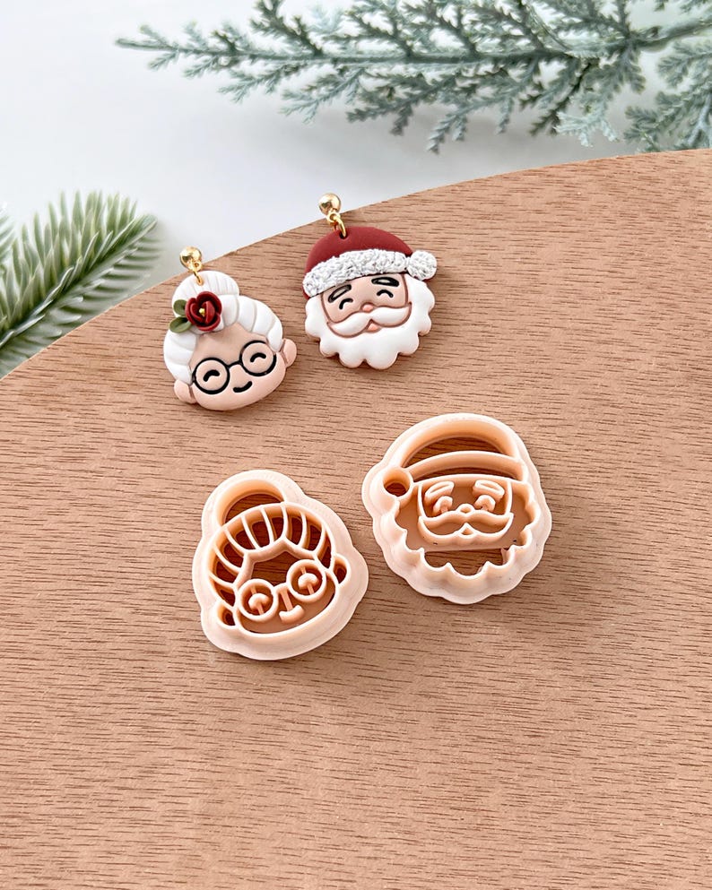 May include: A set of four Christmas cookie cutters featuring Santa Claus and Mrs. Claus. The cutters are made of a light pink plastic and are ready to use for holiday baking.