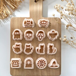 Pu&ograve; includere: Un set di 16 stampini per biscotti a tema Halloween su un tagliere di legno. Gli stampini hanno la forma di un fantasma, un teschio, un pipistrello, un ragno, un gatto, un cappello da strega, una lapide e altro ancora.